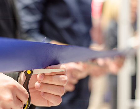 Close up of a person cutting a ribbon.